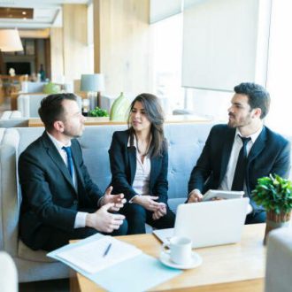 Hispanic professionals planning strategy while sitting with documents and technologies in lobby at hotel